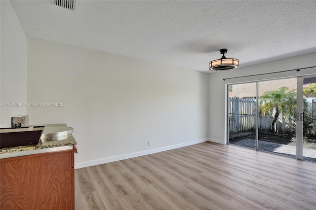 dining space with a textured ceiling and light hardwood / wood-style flooring