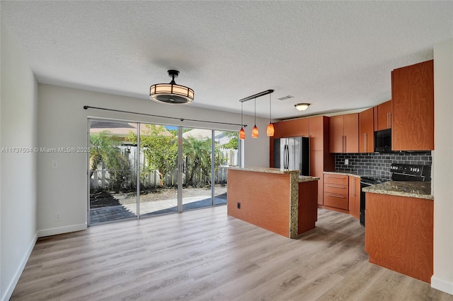 kitchen featuring pendant lighting, decorative backsplash, a center island, black appliances, and light wood-type flooring