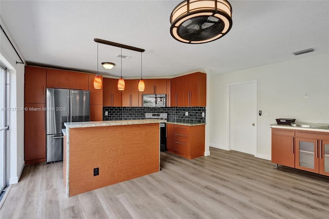 kitchen featuring hanging light fixtures, stainless steel appliances, light hardwood / wood-style floors, a textured ceiling, and decorative backsplash