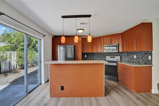 kitchen featuring stainless steel appliances, decorative light fixtures, light hardwood / wood-style flooring, and backsplash