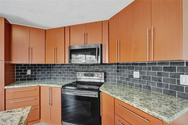 kitchen with appliances with stainless steel finishes, a textured ceiling, light stone counters, and decorative backsplash