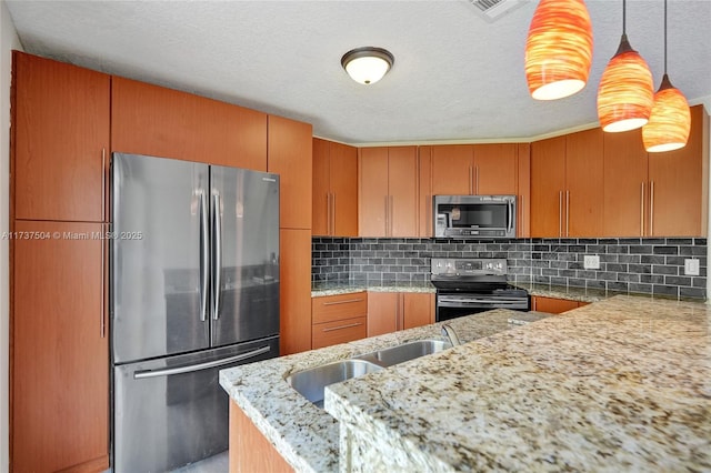 kitchen with appliances with stainless steel finishes, pendant lighting, decorative backsplash, light stone counters, and kitchen peninsula