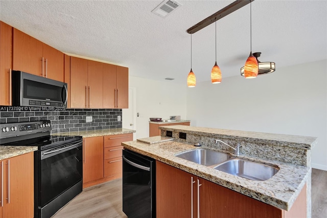 kitchen with hanging light fixtures, light hardwood / wood-style flooring, black appliances, and sink