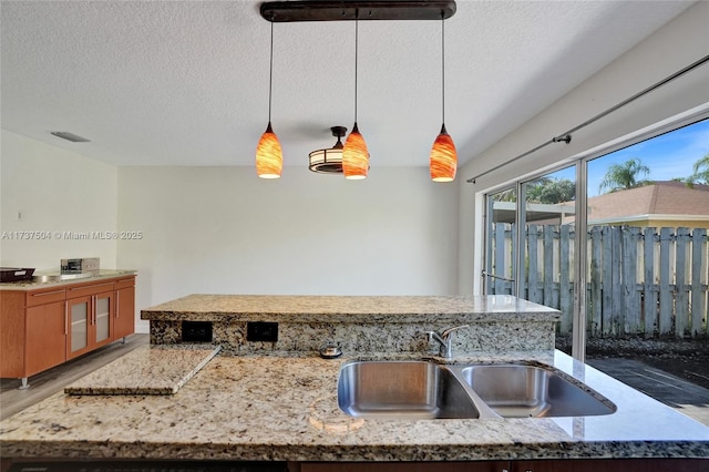 kitchen with pendant lighting, sink, hardwood / wood-style flooring, and a textured ceiling