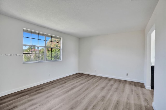 spare room with a textured ceiling and light wood-type flooring