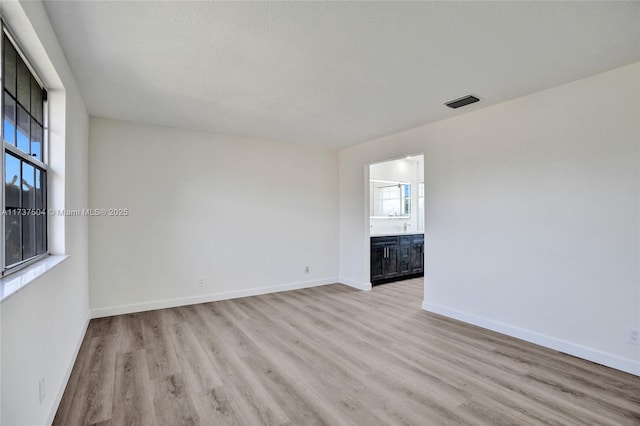 spare room with a textured ceiling and light hardwood / wood-style floors