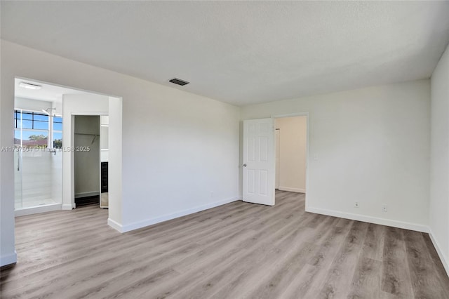 empty room featuring a textured ceiling and light hardwood / wood-style flooring