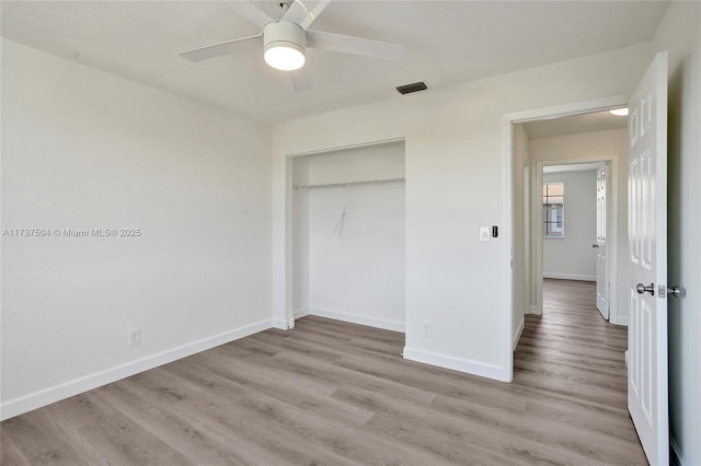 unfurnished bedroom featuring ceiling fan, a closet, and light wood-type flooring