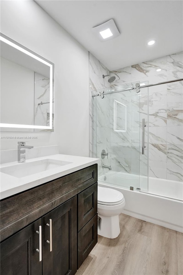 full bathroom featuring toilet, vanity, shower / bath combination with glass door, and hardwood / wood-style floors