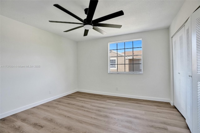 unfurnished bedroom featuring ceiling fan, a closet, light hardwood / wood-style flooring, and a textured ceiling