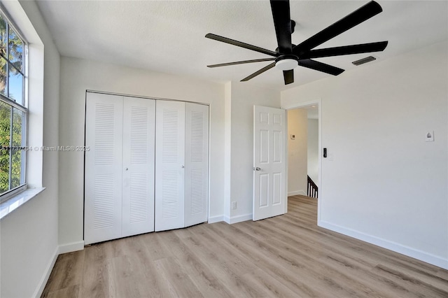 unfurnished bedroom featuring ceiling fan, light hardwood / wood-style floors, and a closet