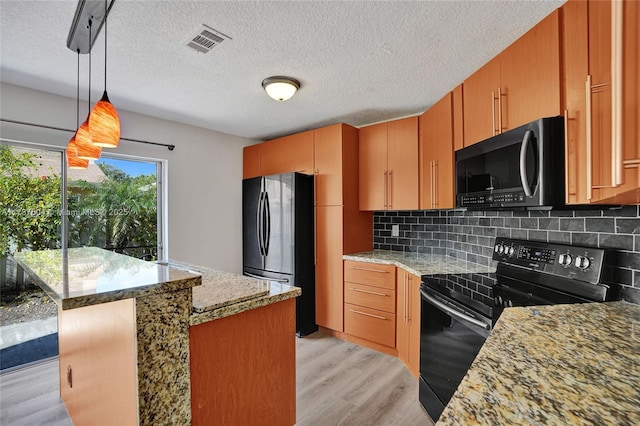 kitchen featuring light stone counters, hanging light fixtures, light hardwood / wood-style floors, decorative backsplash, and black appliances