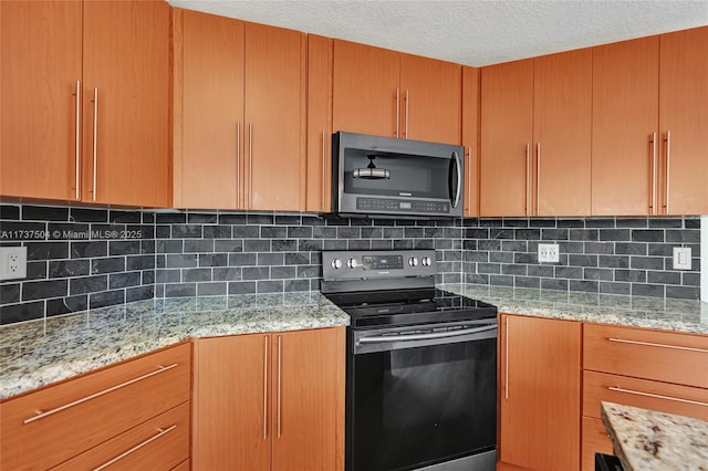 kitchen with tasteful backsplash, appliances with stainless steel finishes, a textured ceiling, and light stone counters