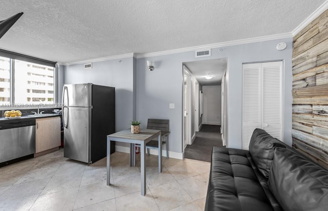 kitchen with appliances with stainless steel finishes, sink, light tile patterned floors, crown molding, and a textured ceiling