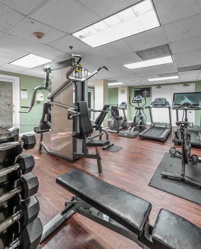 gym with dark wood-type flooring and a paneled ceiling