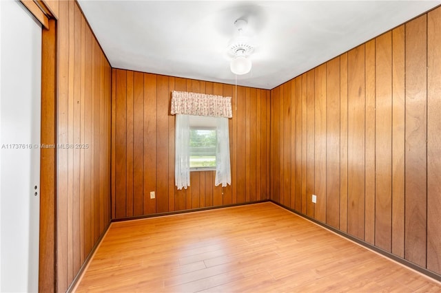 empty room featuring wood walls and light wood-type flooring