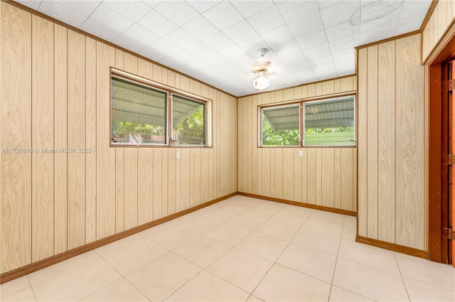 spare room with ornamental molding, wooden walls, and a wealth of natural light