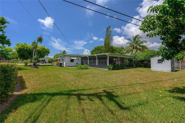 back of property featuring a storage shed, a yard, and a sunroom