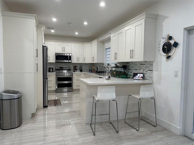 10290 SW 7th Ter, Sweetwater, FL 33174 - kitchen with visible vents, a peninsula, a sink, stainless steel appliances, and backsplash