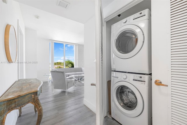 clothes washing area featuring stacked washer and dryer and hardwood / wood-style floors