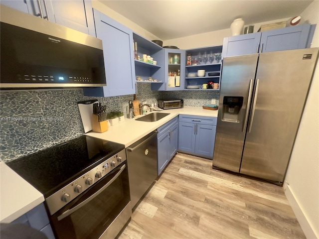 kitchen featuring sink, stainless steel appliances, tasteful backsplash, blue cabinets, and light wood-type flooring