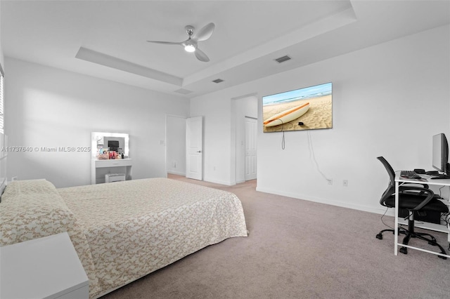 carpeted bedroom featuring ceiling fan and a raised ceiling