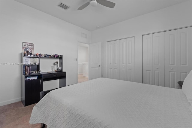 bedroom with two closets, carpet floors, and ceiling fan