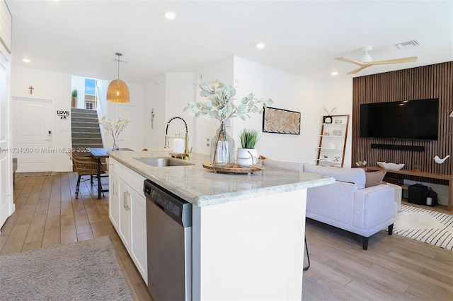 kitchen with sink, white cabinetry, decorative light fixtures, stainless steel dishwasher, and a kitchen island with sink