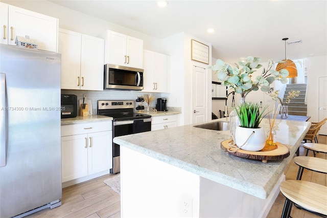 kitchen featuring stainless steel appliances, an island with sink, and white cabinets