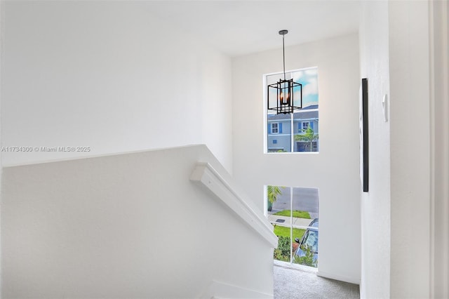 stairs featuring carpet flooring and a notable chandelier