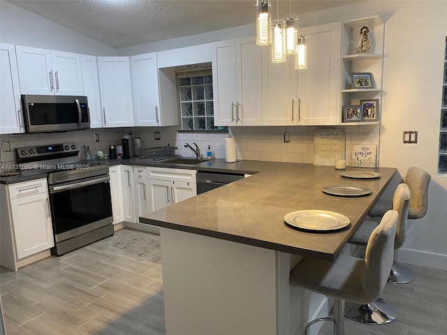 kitchen featuring stainless steel appliances, white cabinetry, and kitchen peninsula