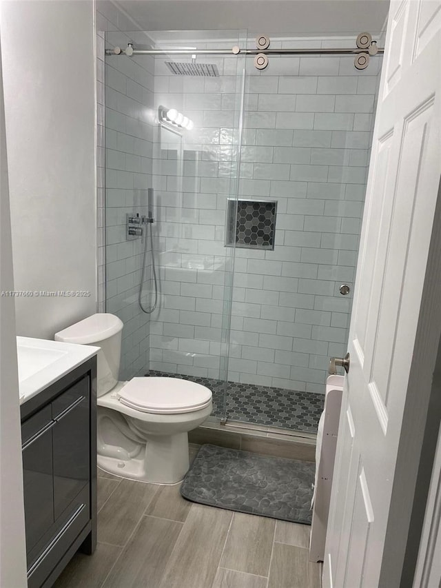 bathroom featuring vanity, toilet, and a shower with shower door