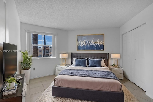 bedroom featuring light tile patterned flooring, a textured ceiling, and a closet