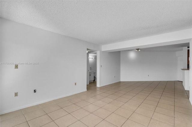 tiled empty room featuring a textured ceiling