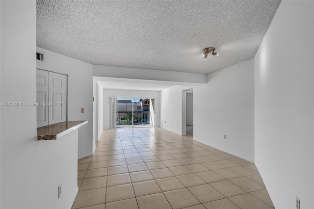 empty room with light tile patterned floors and a textured ceiling