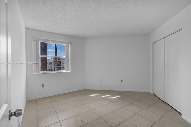 unfurnished bedroom with light tile patterned flooring, a textured ceiling, and a closet