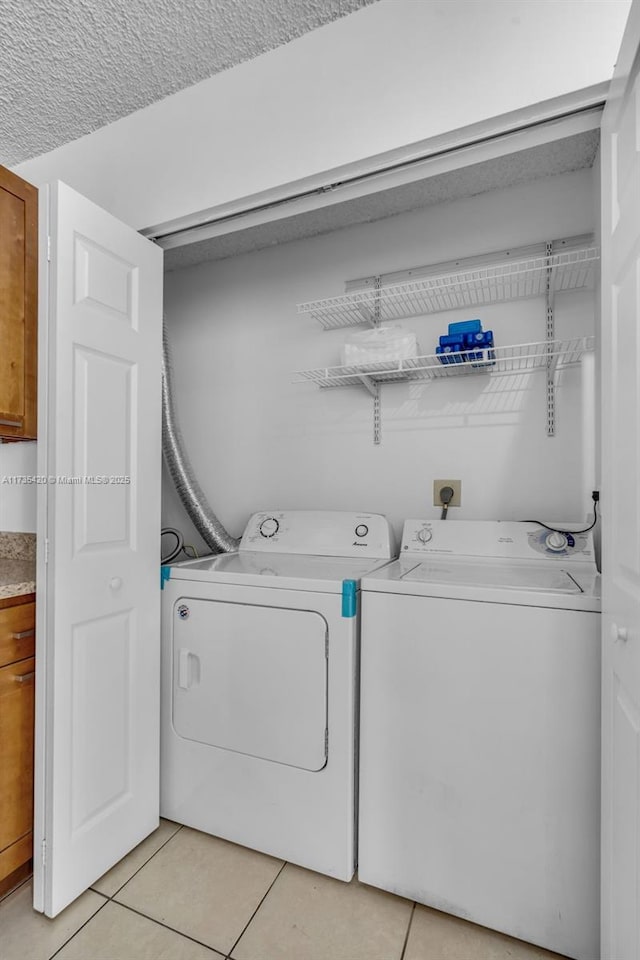 laundry area with washer and dryer and light tile patterned floors