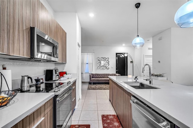 kitchen featuring light tile patterned flooring, appliances with stainless steel finishes, decorative light fixtures, and sink