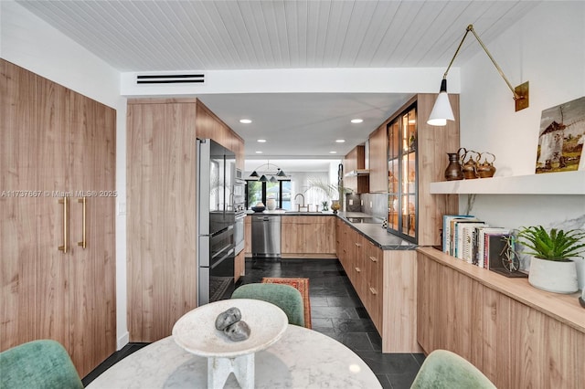 kitchen with appliances with stainless steel finishes, sink, pendant lighting, and kitchen peninsula