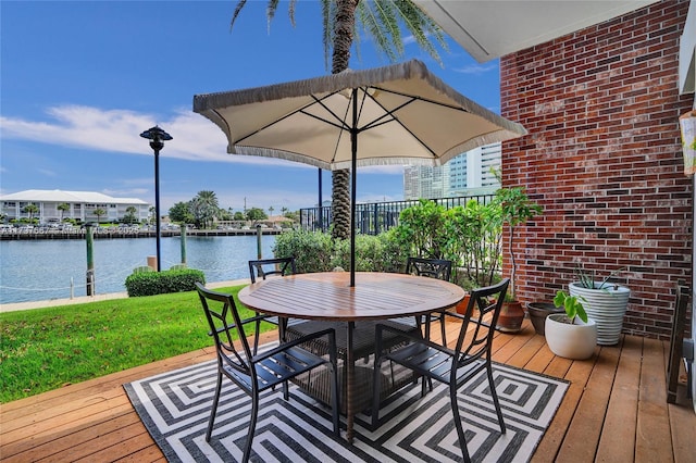 wooden deck with a water view and a lawn