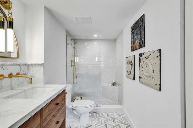 bathroom with vanity, tasteful backsplash, toilet, and tiled shower