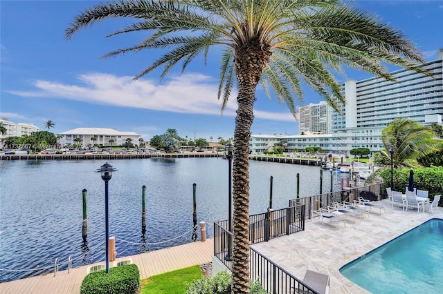 view of dock with a patio, a water view, and a community pool