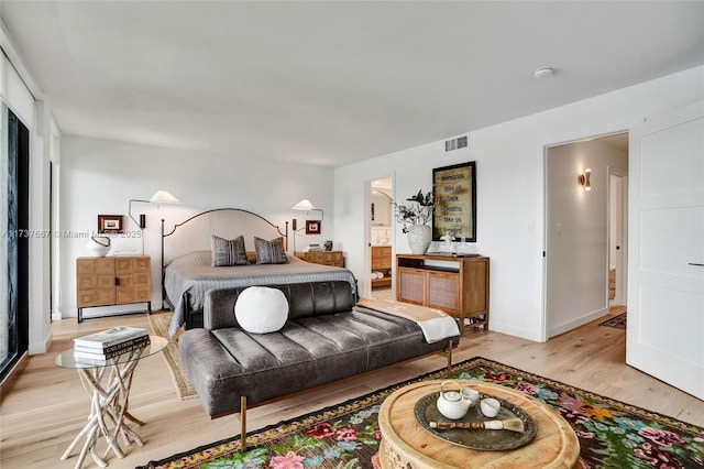 bedroom featuring connected bathroom, light hardwood / wood-style flooring, and a baseboard heating unit