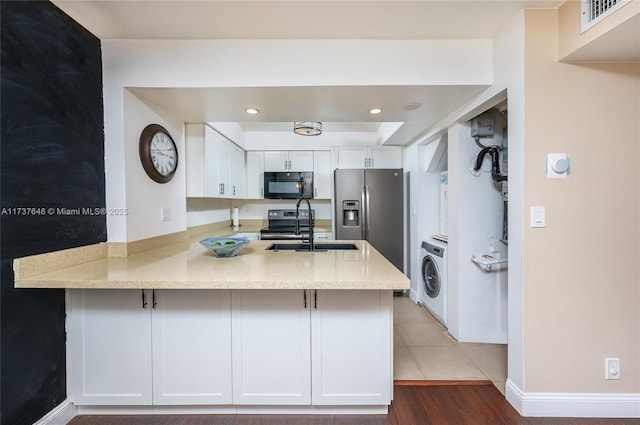 kitchen with white cabinetry, kitchen peninsula, and washer / dryer