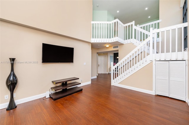 unfurnished living room with a towering ceiling and hardwood / wood-style floors