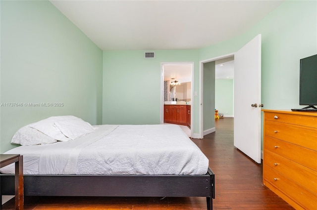 bedroom featuring ensuite bath and dark hardwood / wood-style flooring