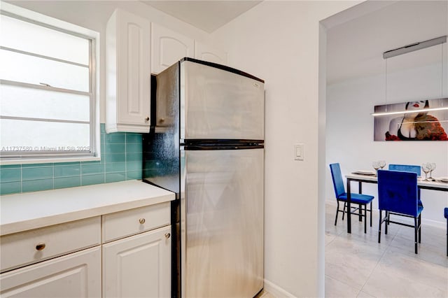 kitchen featuring tasteful backsplash, white cabinets, and stainless steel refrigerator