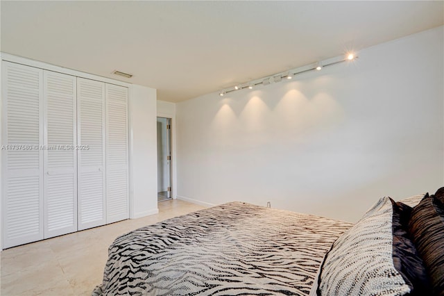 bedroom featuring rail lighting and a closet