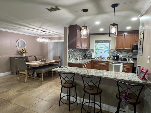 kitchen with ornamental molding, kitchen peninsula, pendant lighting, stainless steel appliances, and light stone countertops