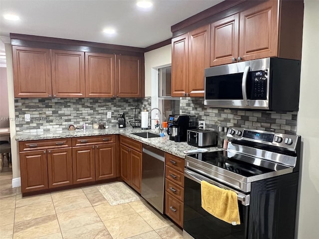 kitchen with light stone counters, appliances with stainless steel finishes, sink, and backsplash